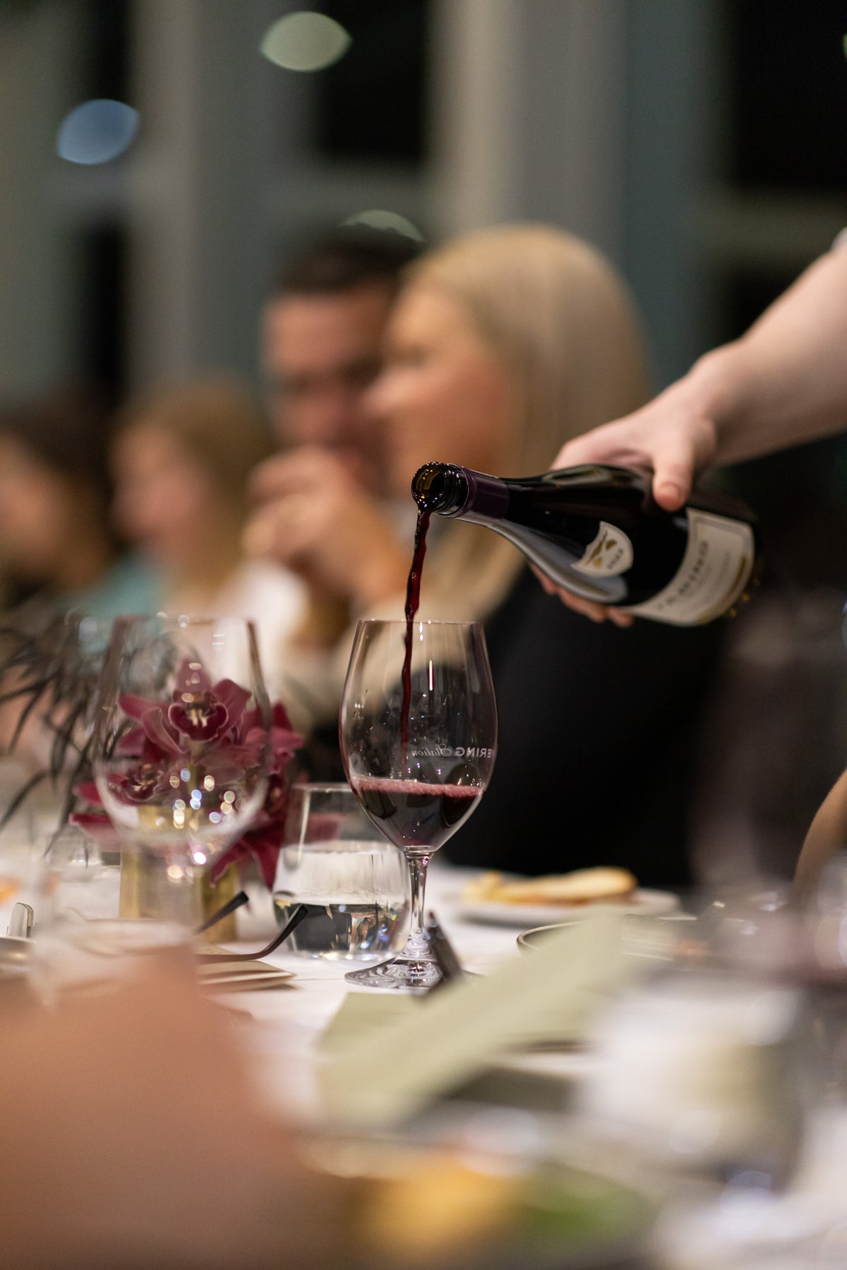 Waiter pouring red wine into a glass at a decorated dinner table