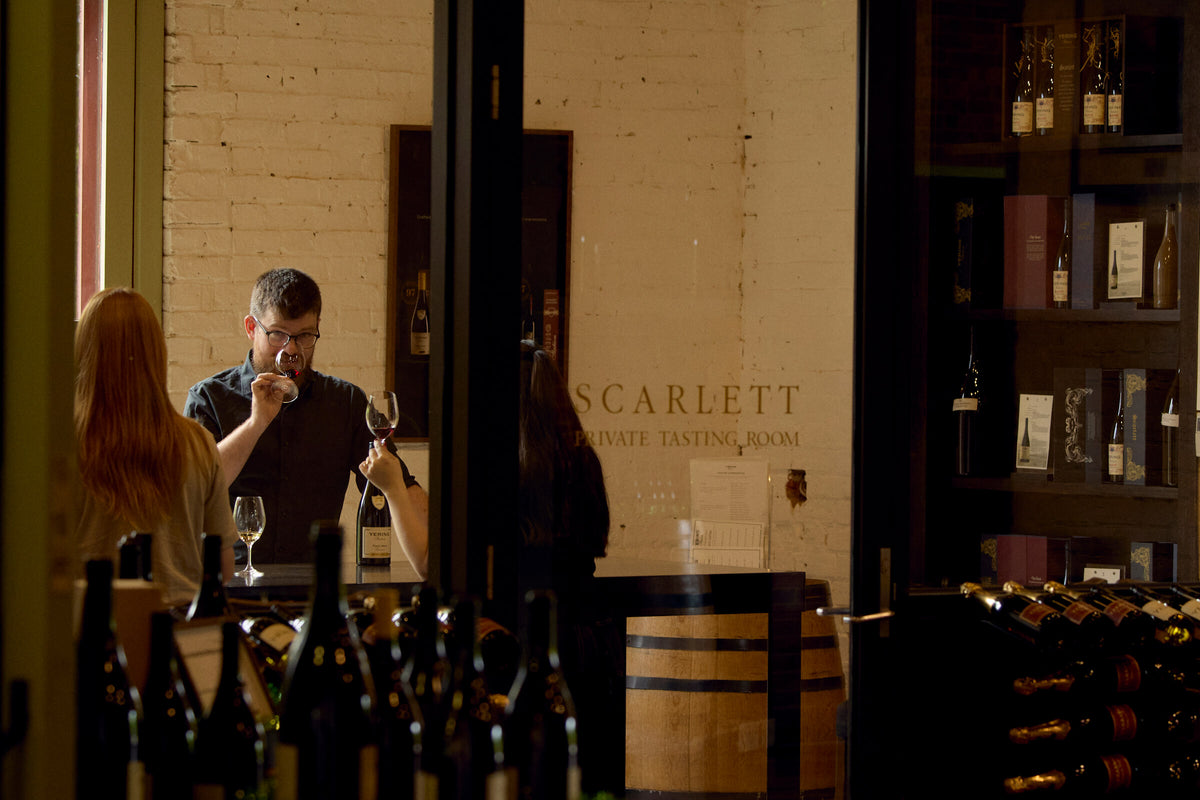 Guests tasting wine in the Scarlett Private Tasting Room surrounded by wine bottle displays