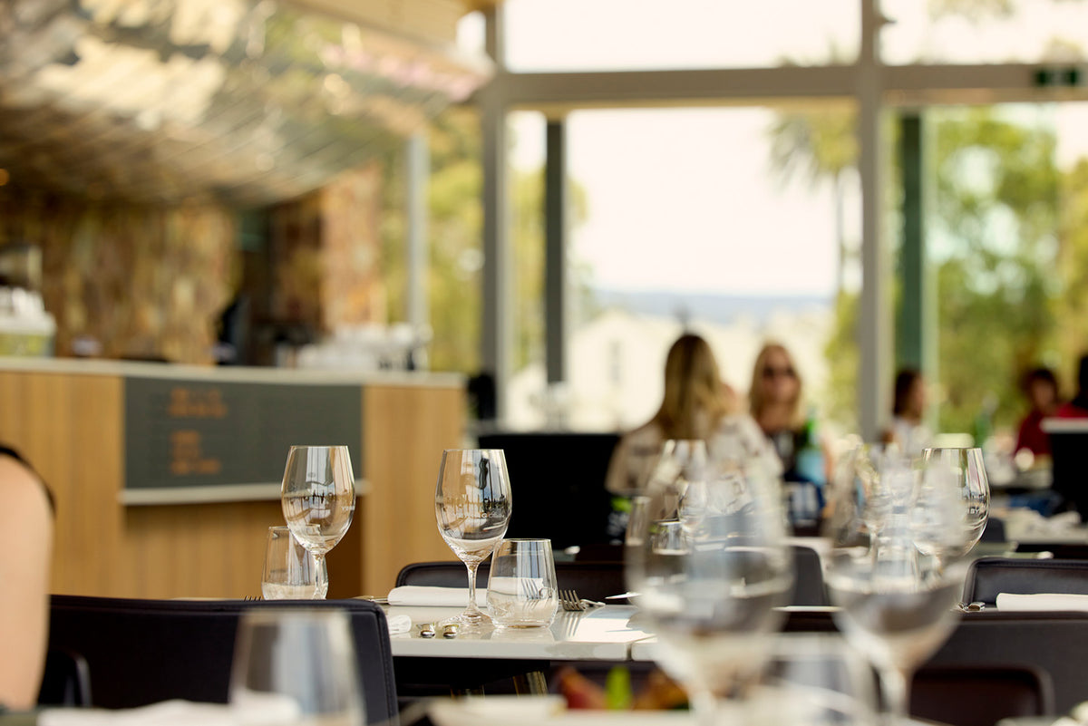 Restaurant dining room with wine glasses on tables and diners seated near large windows