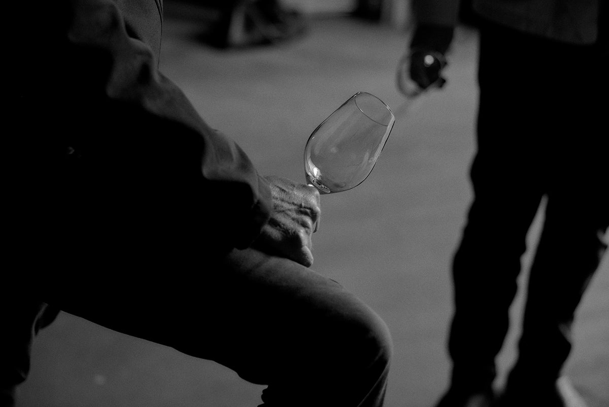 Black and white close-up of a hand holding an empty wine glass at an event