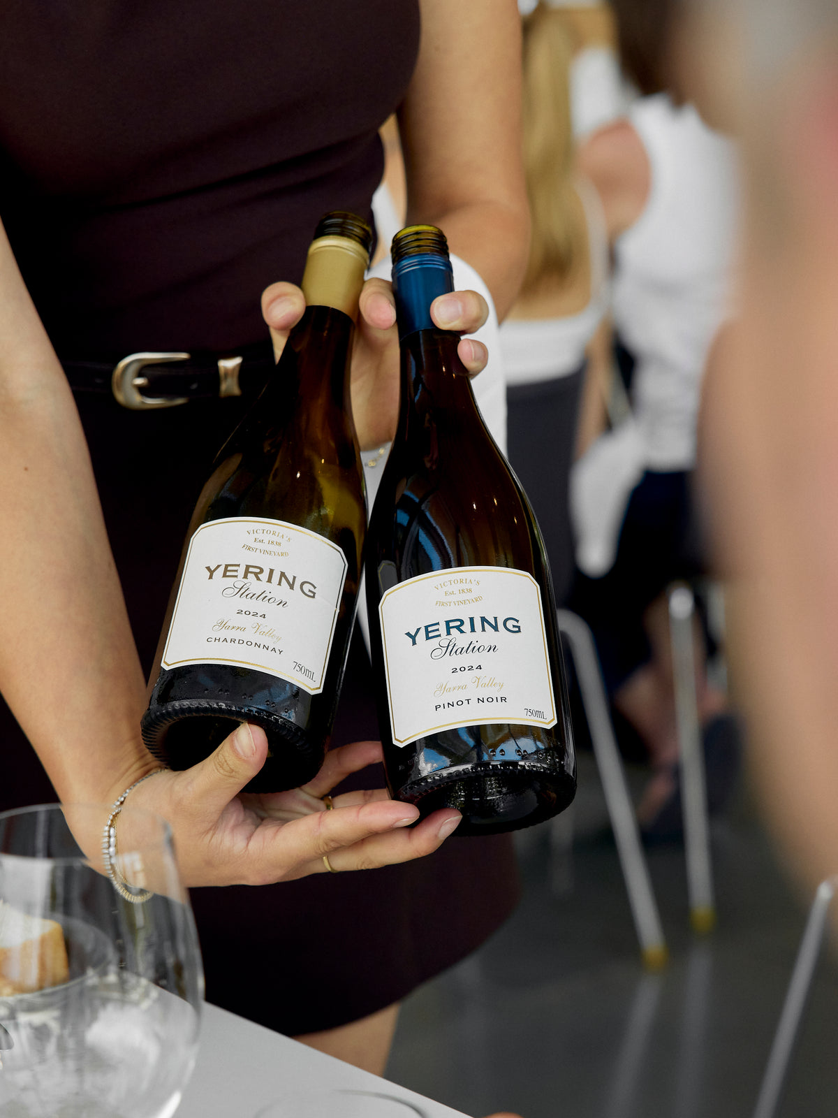 Staff member presenting two Yering Station wine bottles, a Chardonnay and a Pinot Noir