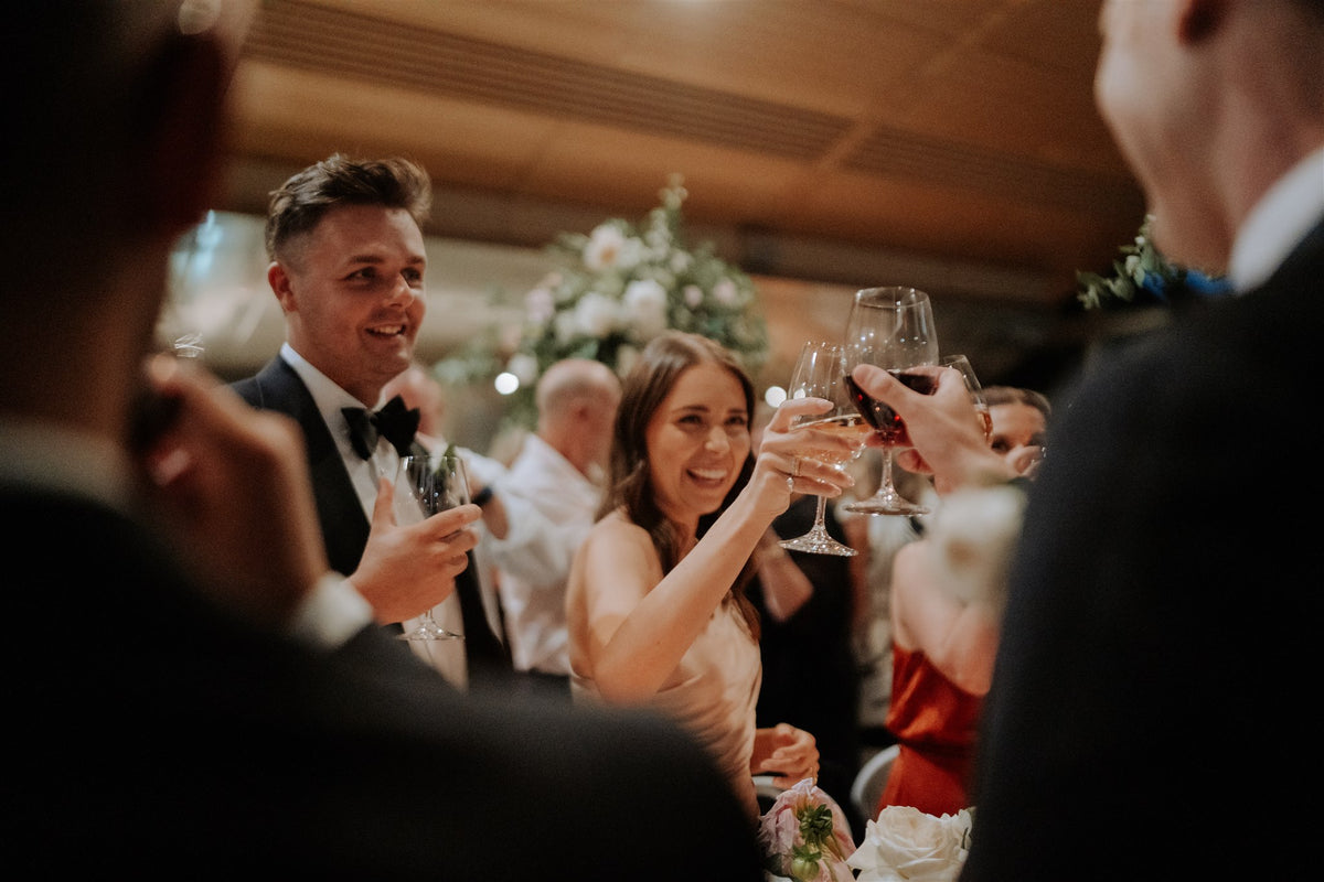 Wedding guests raising wine glasses in a toast during an indoor reception