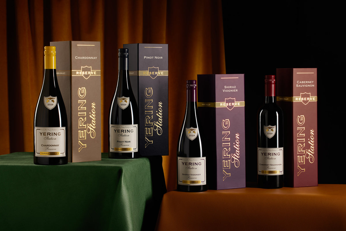 Four Yering Station Reserve wine bottles displayed alongside their gift boxes on a draped table