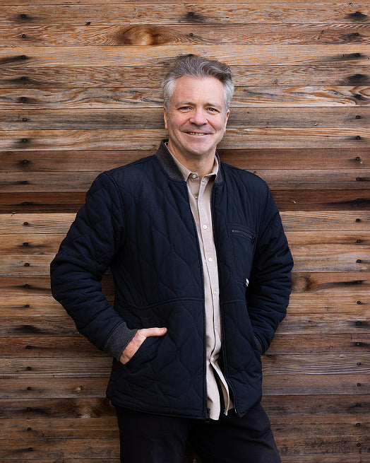 Portrait of Darren Rathbone, a member of the Yering Station team, smiling against a timber wall
