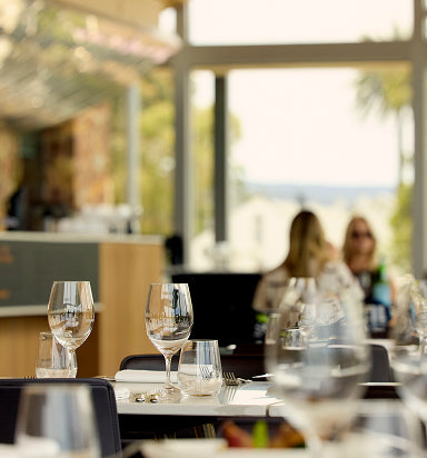 Restaurant interior with wine glasses on the table and guests chatting by the window