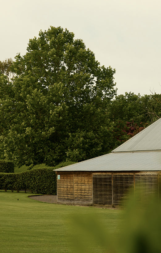 Historic wooden barn with a corrugated roof beside a grassy lawn
